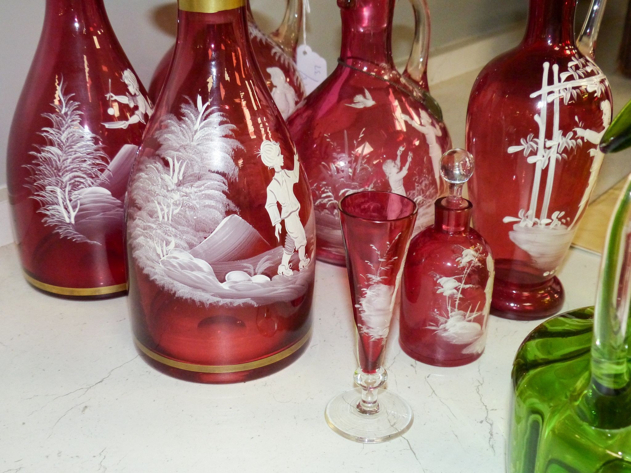 A collection of Mary Gregory cranberry and green glass decanters, jug etc (9), tallest 28.5 cm